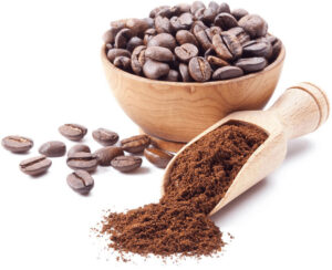 Wooden bowl full of roasted coffee beans with scattered beans and a wooden scoop spilling ground coffee on a white background.